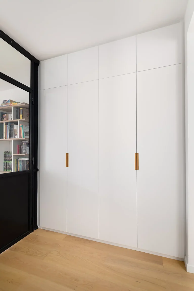 Dressing intégré dans le mur avec poignées bois naturel et façades blanches mates